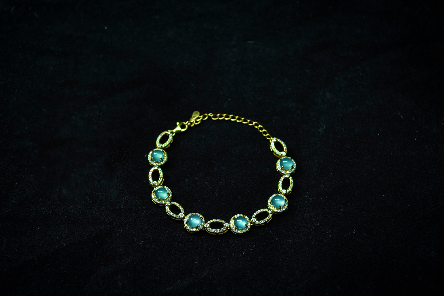 Gold bracelet with turquoise stones on a dark background
