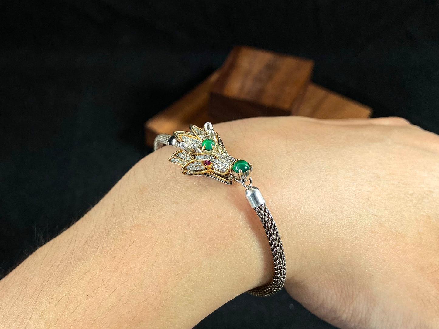 A dragon pendant bracelet featuring a 925 silver body accented with imperial green jade spheres on the head and mouth.