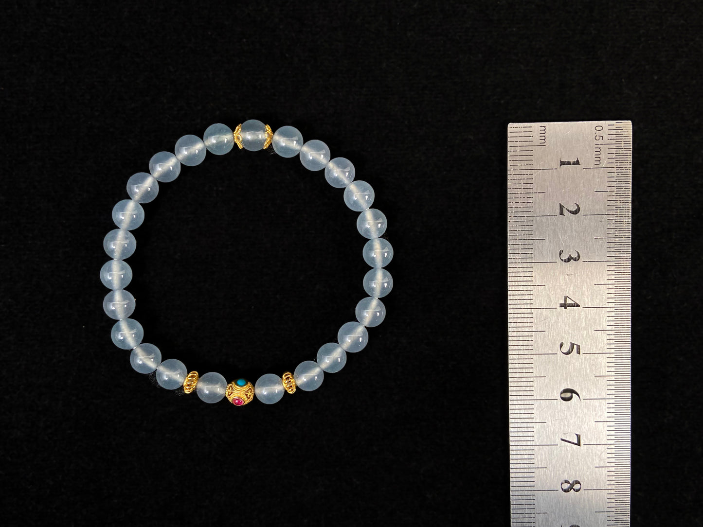 This bracelet combines icy jadeite beads with a hollow 18K gold center bead.