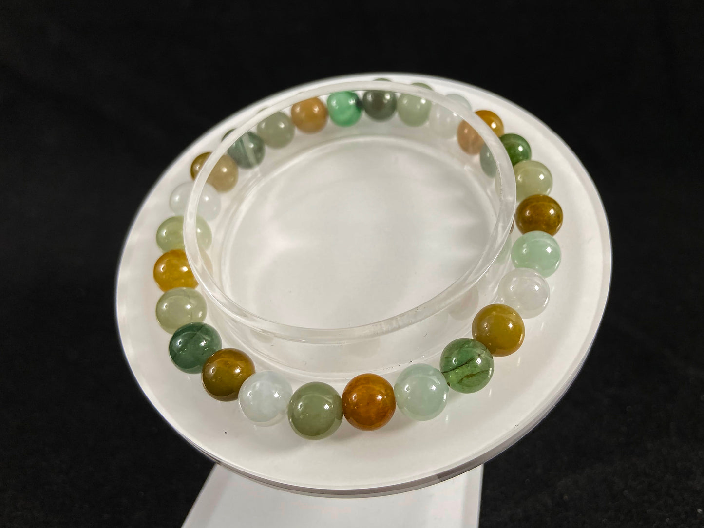 This jade bead strand features a natural palette of green, white, brown, olive, and yellow tones.