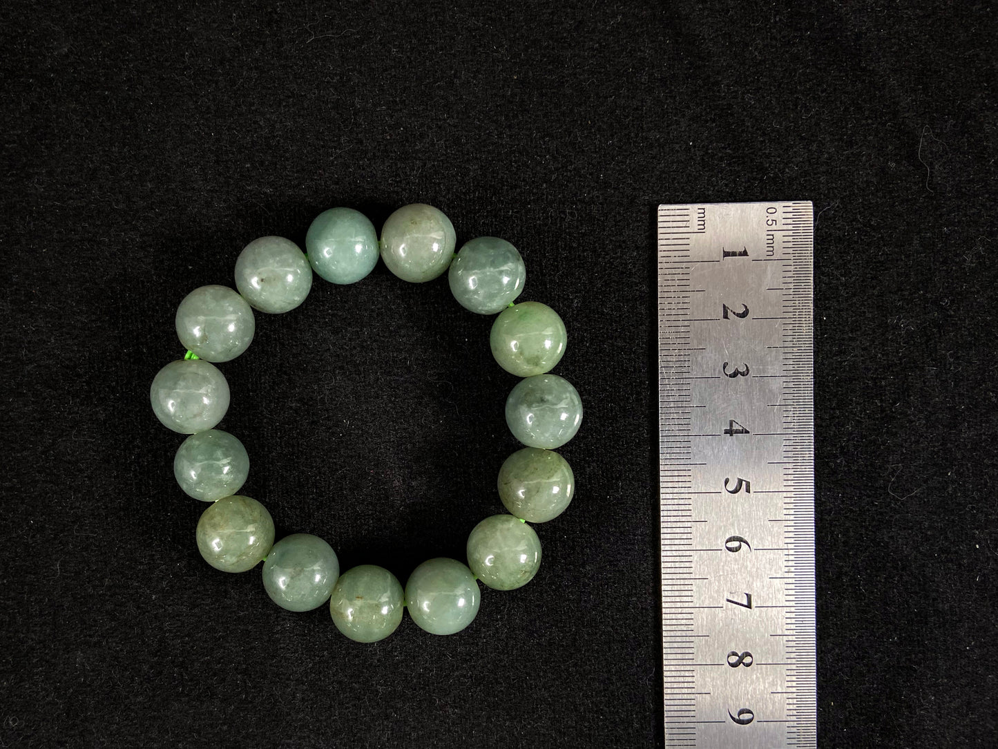 This jadeite bead strand features uniformly sized beads with a green base, accented by gold on some beads.