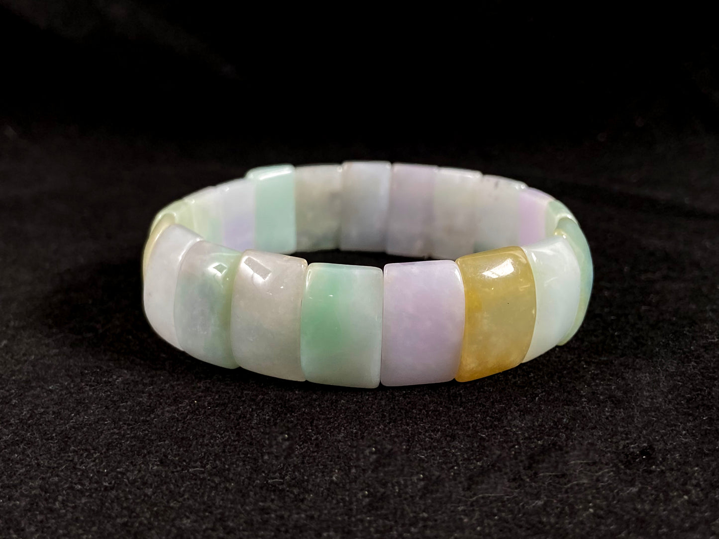 A rectangular jade bangle featuring an earthy palette of green, cream, purple and brown.