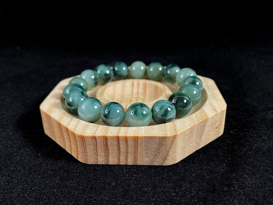 This jadeite bead strand has beads of the same size each translucent one with a soft white green base, dotted with dark green.