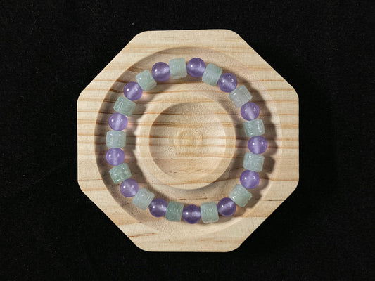 A jade bead strand featuring transparent purple spheres and semi transparent white cylinders.