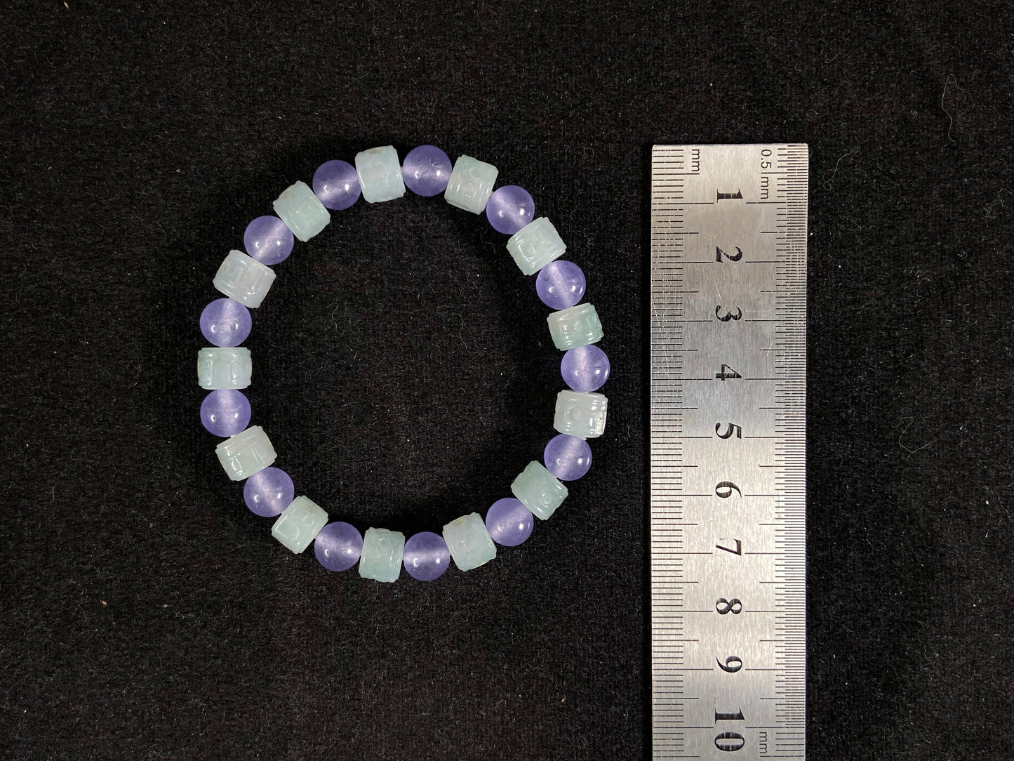 A jade bead strand featuring transparent purple spheres and semi transparent white cylinders.