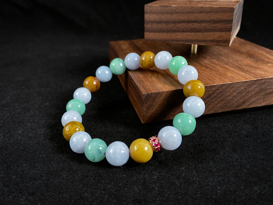 A jade bead strand combining yellow, brown, creamy white, and light green beads, accented with a rose gold alloy cylinder.