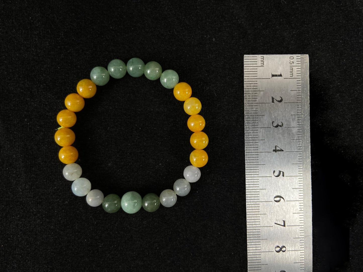 A jade bead strand featuring yellow, deep green, light green, and white-purple beads.