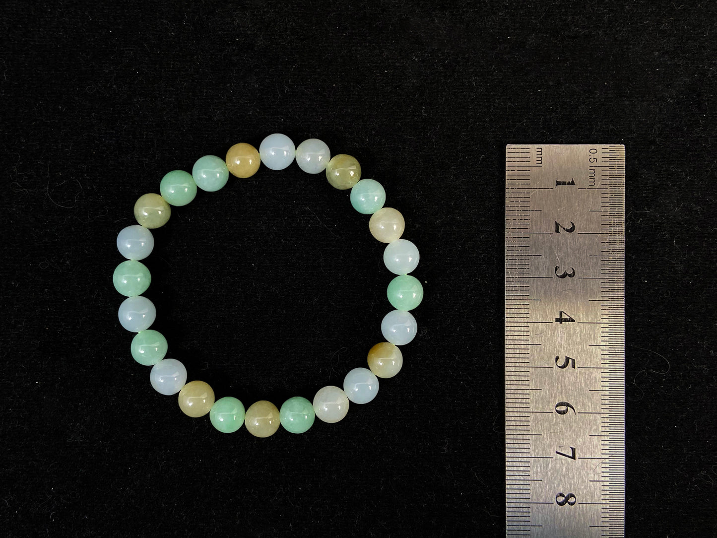 A jade bead strand featuring apple green, yellow, brown, and icy white hues.