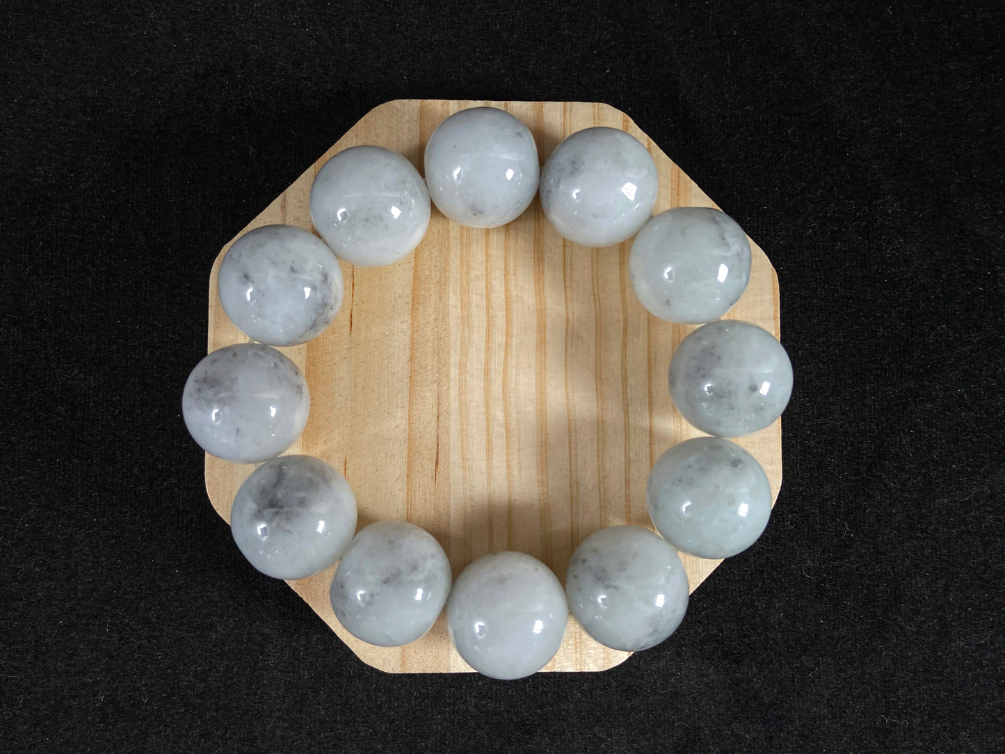 A jade bead strand featuring creamy white beads with gray speckles.