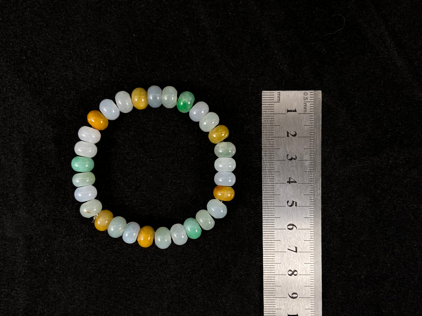 A jade bead strand featuring green, brown, yellow, white, and icy toned beads.