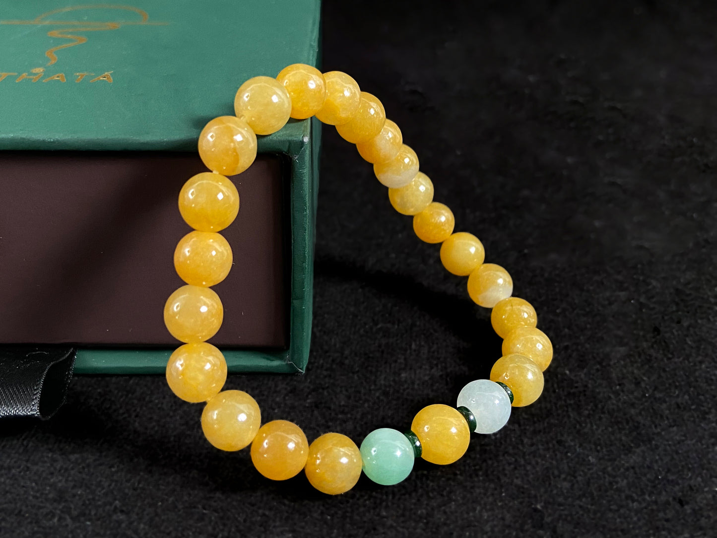This jade bracelet has mostly yellow beads, plus one apple green and one creamy white bead.