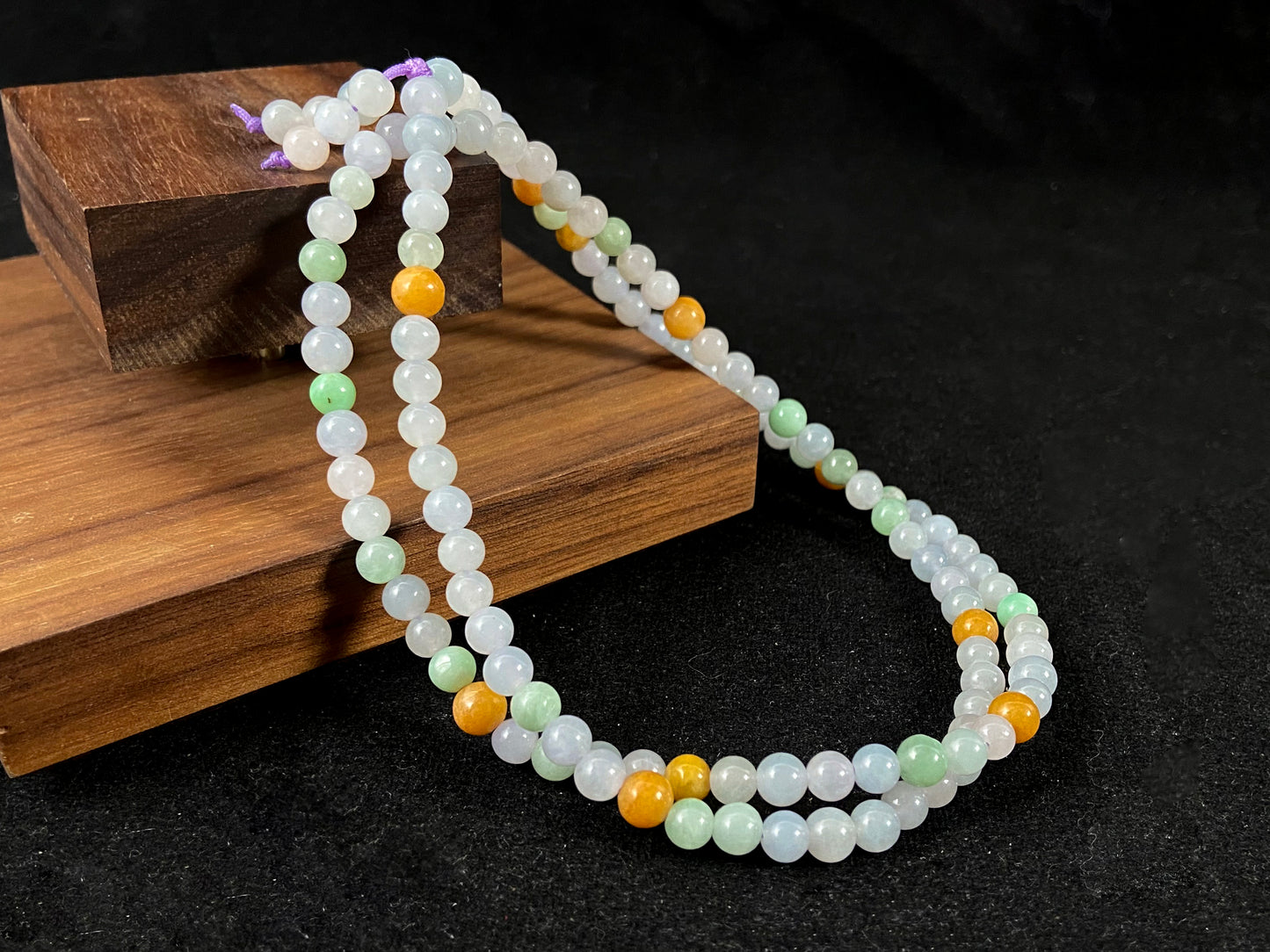A jade bead strand primarily featuring icy, light green, and golden beads.