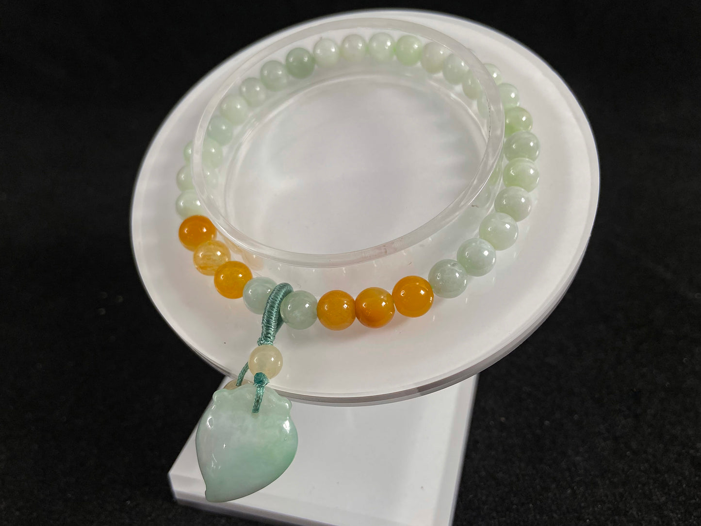 A jade bead strand with a white green peach pendant and tan/white green beads.