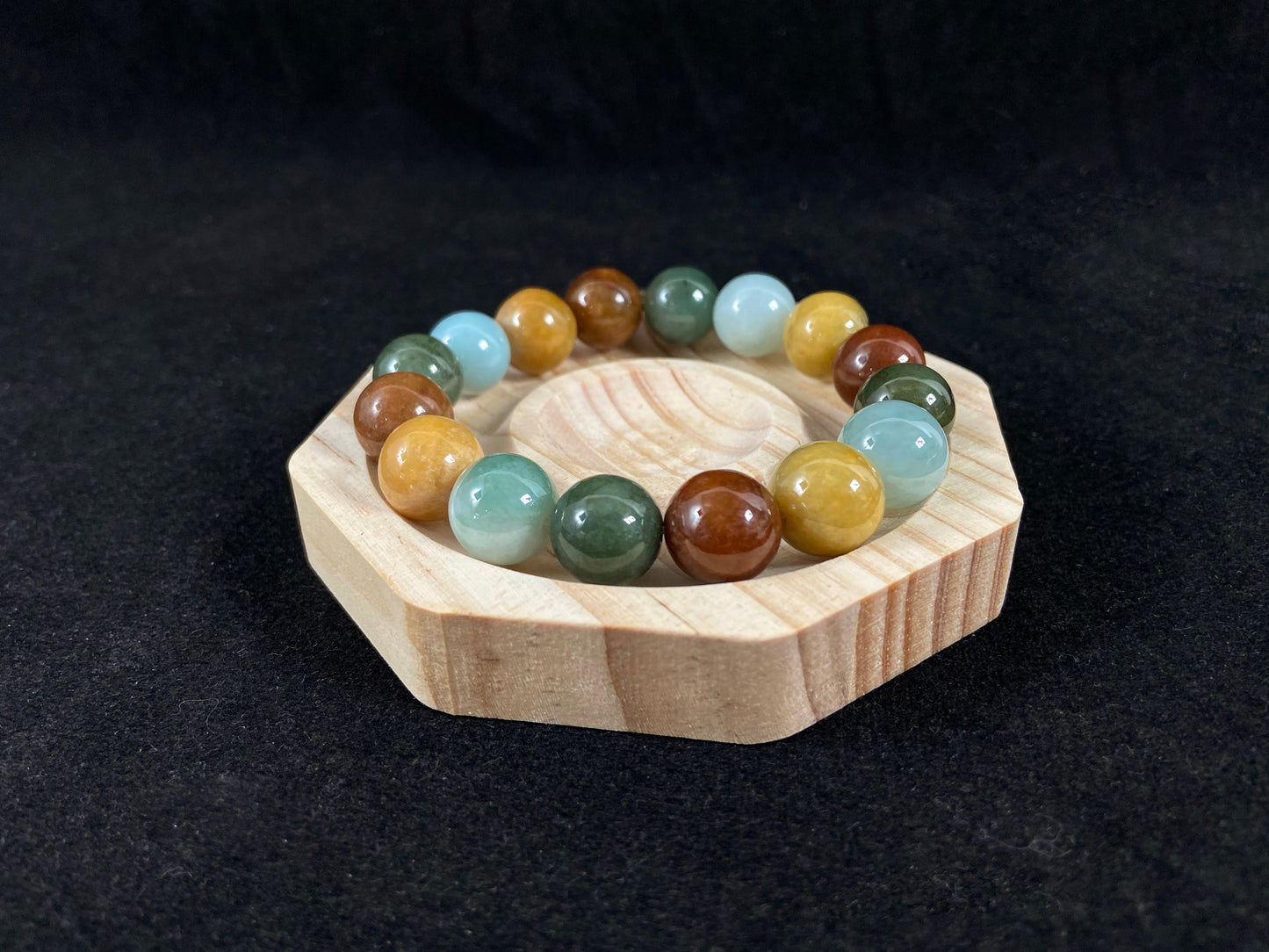 A jade bead strand in soft blue, deep green, reddish-brown and yellow.