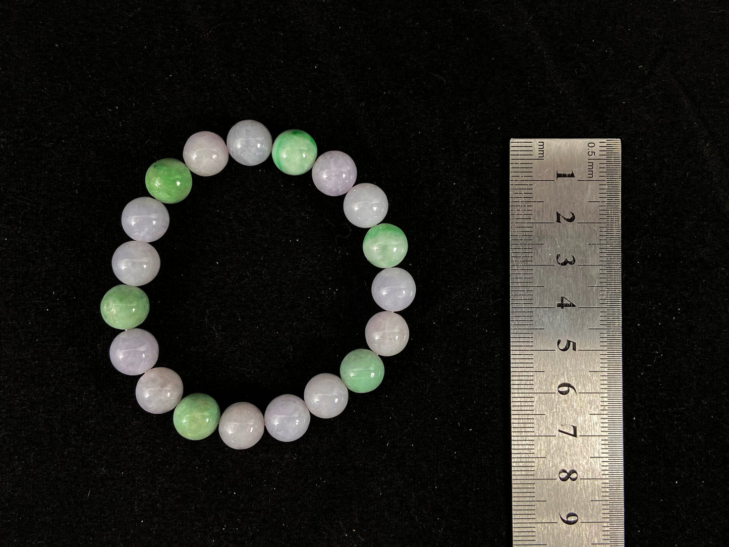 A strand of uniform pale lavender-white jade beads featuring six strategically placed icy green white accent beads.