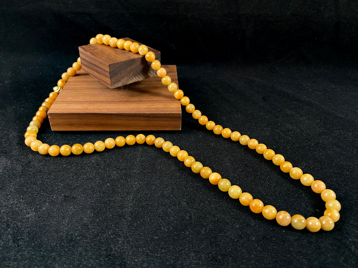 A strand of yellow jade beads featuring an alloy accented piece.