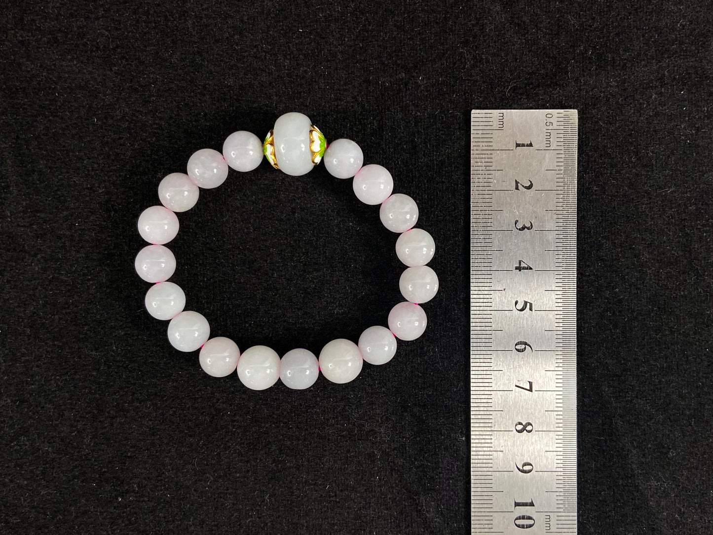 A milky white jade bead strand featuring a central focal bead accented with white green petal shaped alloy sidepieces.