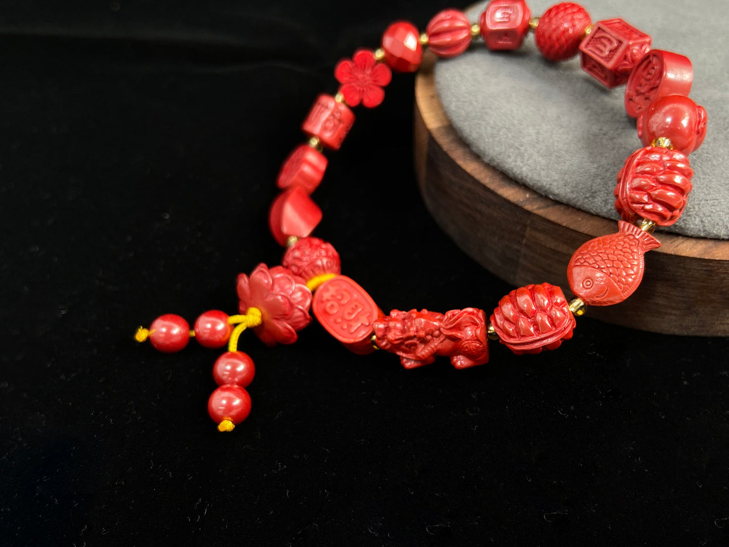 This cinnabar bracelet showcases an array of symbolic beads in pumpkin, peach blossom, fortune, and fish shapes, complete with a lotus charm and four rotating beads.