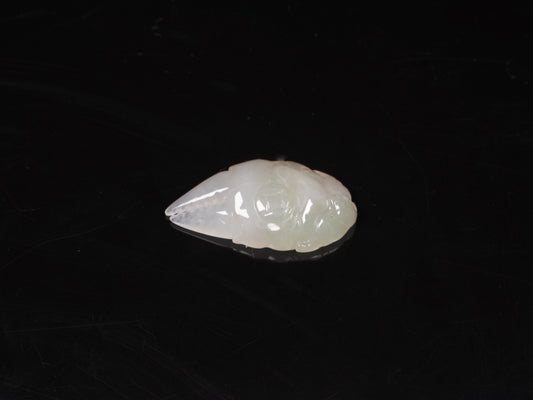 A crab-claw shaped jadeite piece with a milky white base and a subtle wash of pale green.