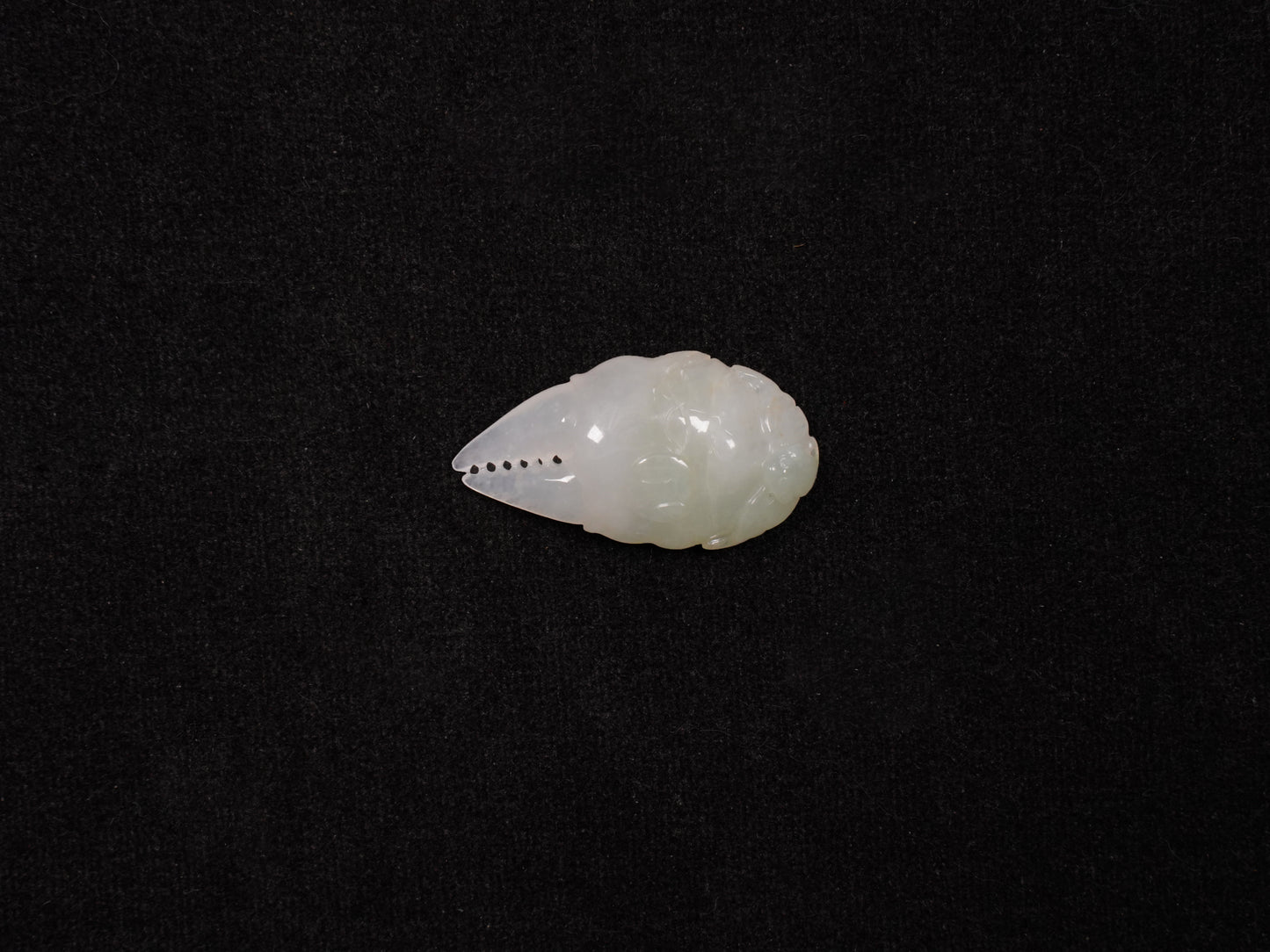 A crab-claw shaped jadeite piece with a milky white base and a subtle wash of pale green.