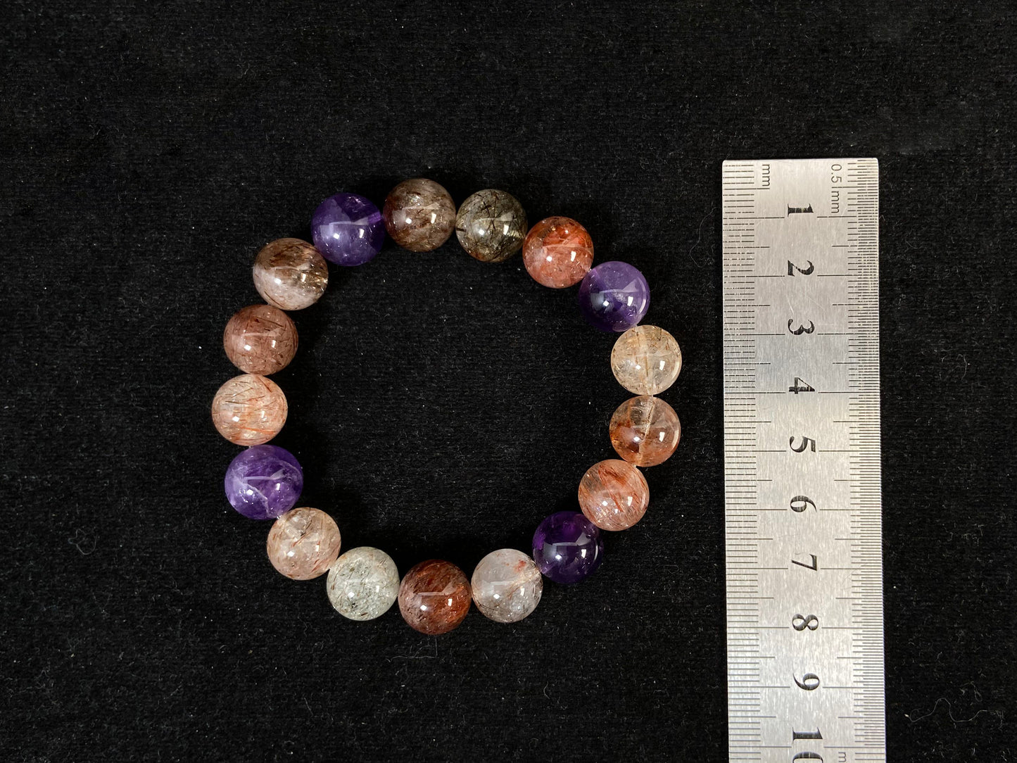 Super 7 crystal beads, a natural inclusion stone with hair-like, flaky, and speckled patterns in vibrant purple, red, orange, and black.