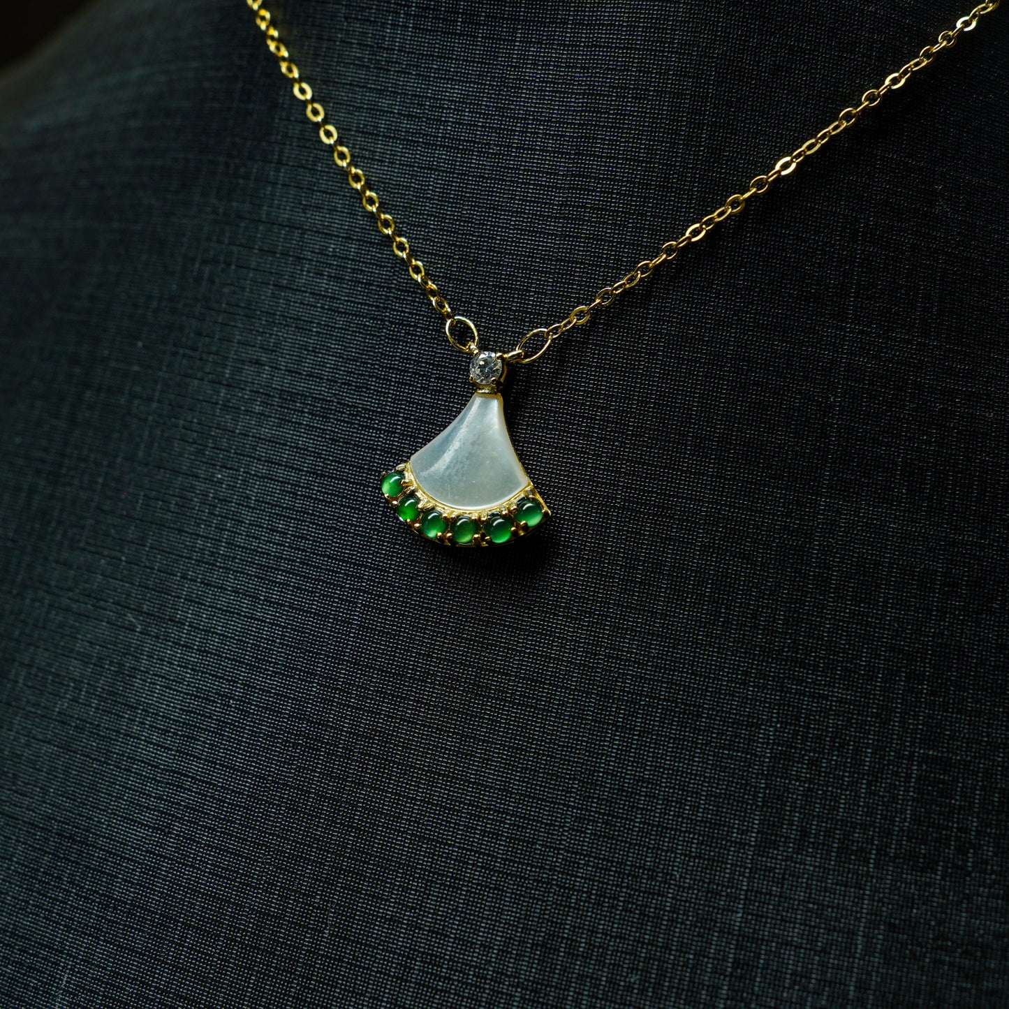 Necklace with a pendant featuring a green gemstone on a black background