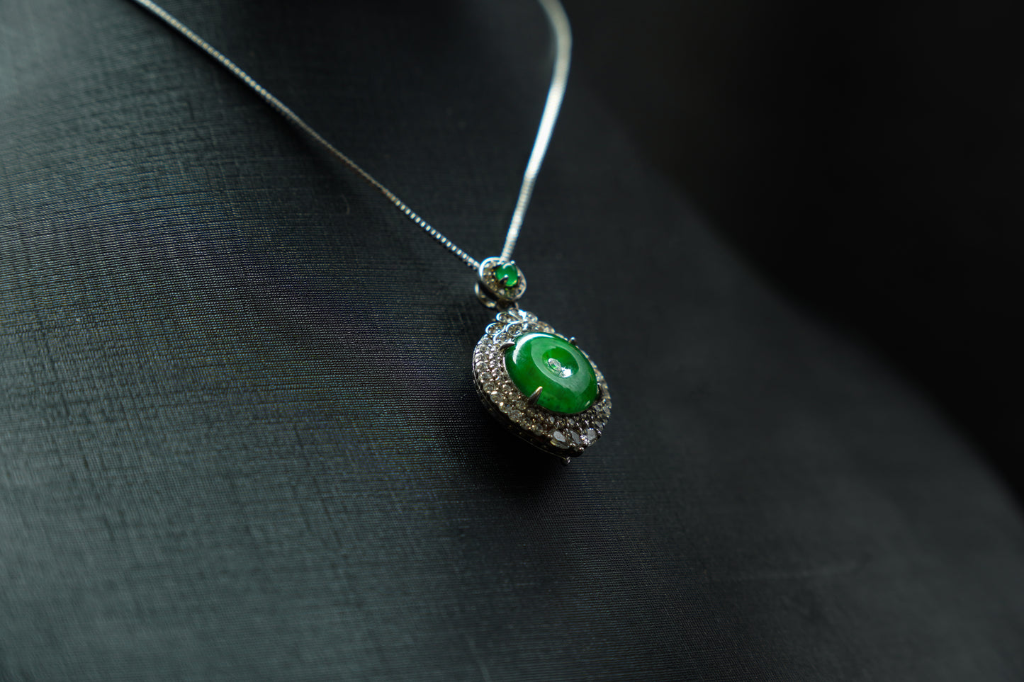 Green gemstone necklace on a dark fabric background
