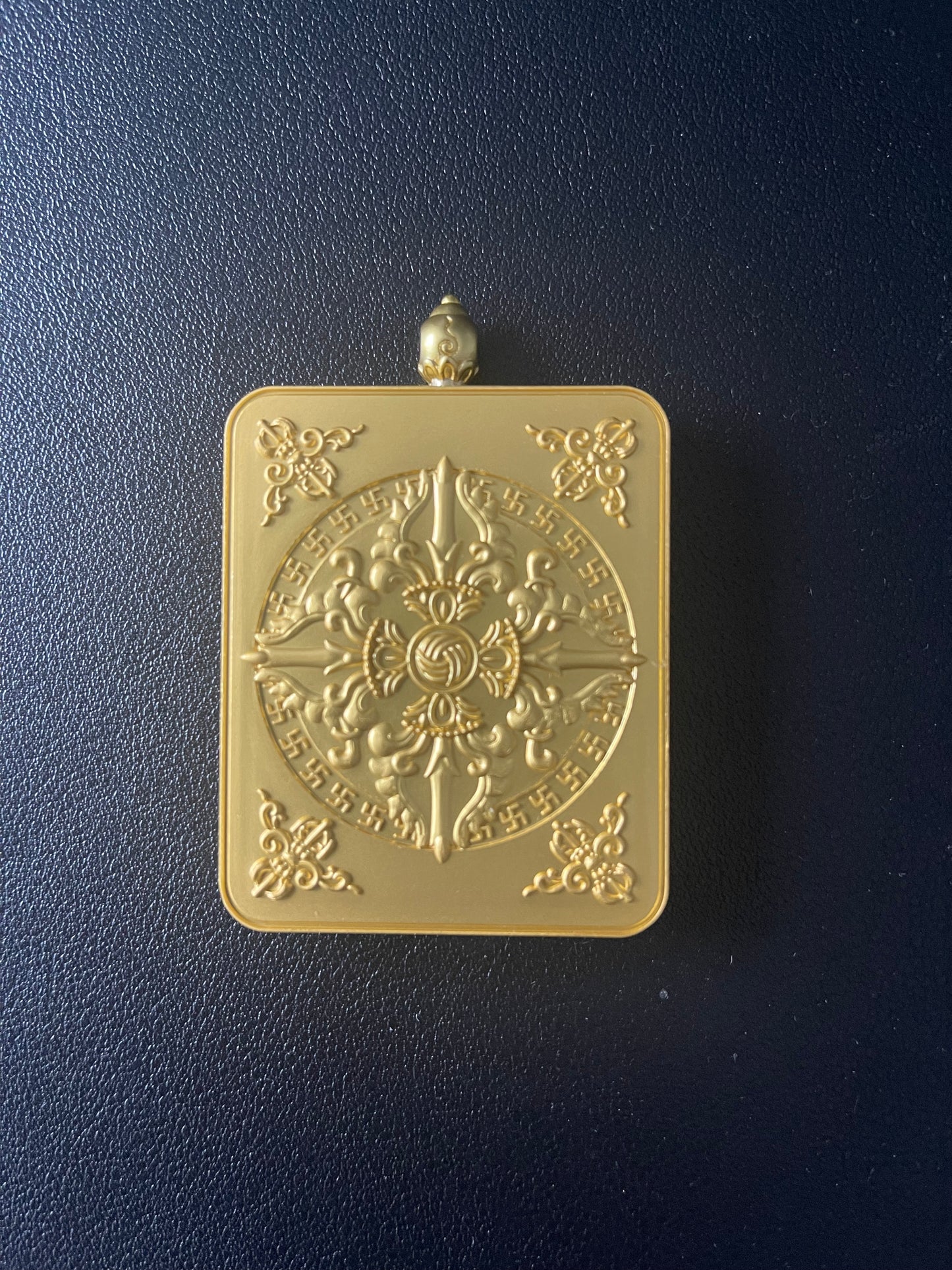 Gold decorative plaque with intricate design on a dark blue background