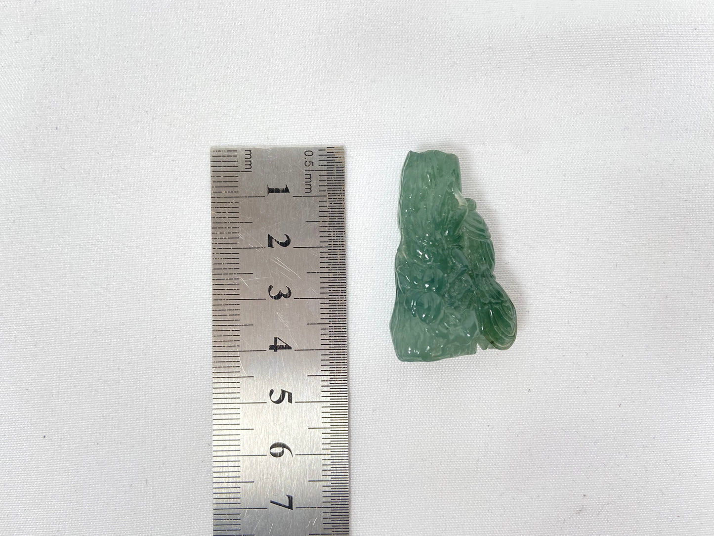 A transparent light green jadeite carved with a cicada on a tree trunk.