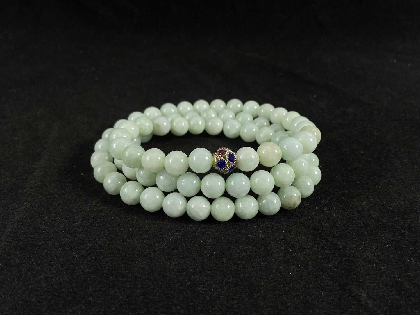 A jade bead strand in a pale whitish green hue.
