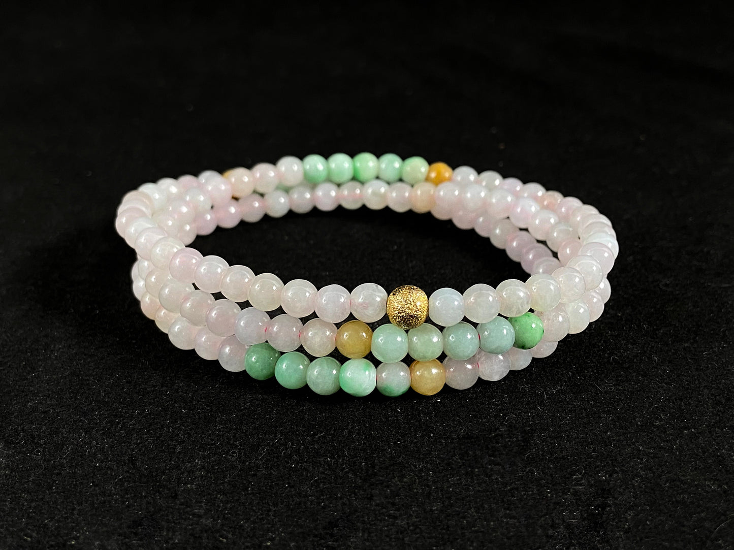 A jade bead strand featuring icy, white green, yellow, and brown beads with a golden focal bead.