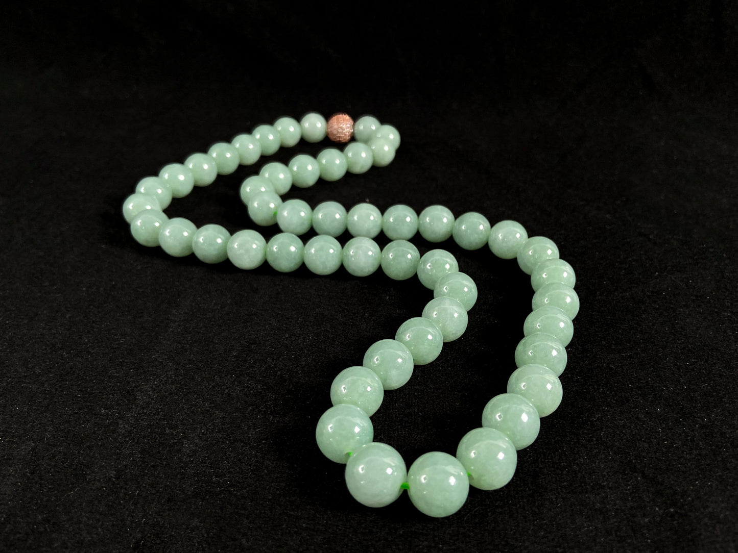 A jade bead strand featuring a gold mesh focal bead amid apple green beads.