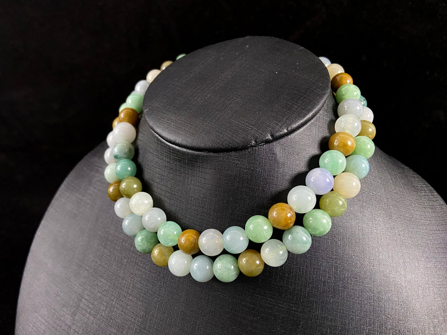 A jade bead strand featuring green, brown, pale yellow, white, and bluish purple beads.