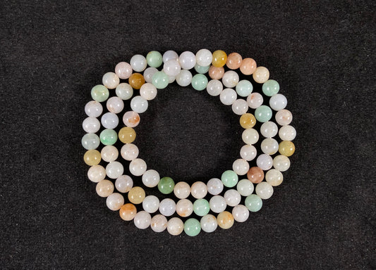 A jade bead strand featuring light green, tan, forest green, creamy white, and orange hues.