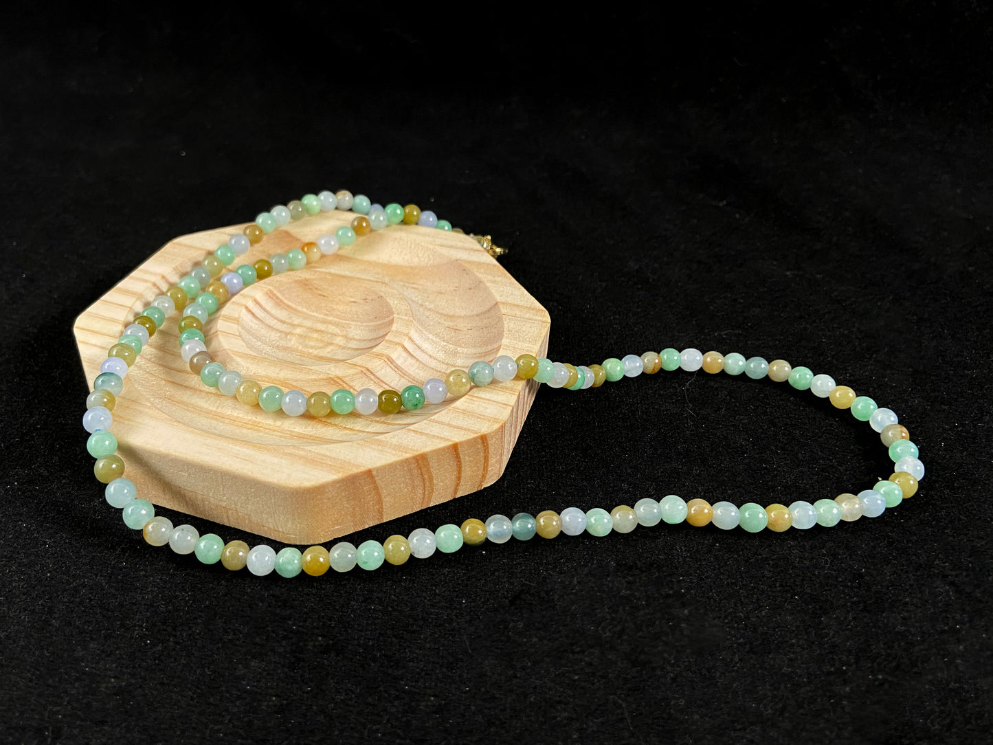 A jade bead strand featuring light green, creamy white and green beads