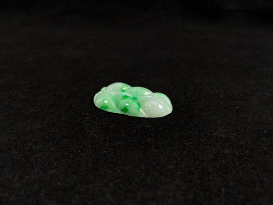 A jadeite loose stone with a milky white base and vibrant green patches.