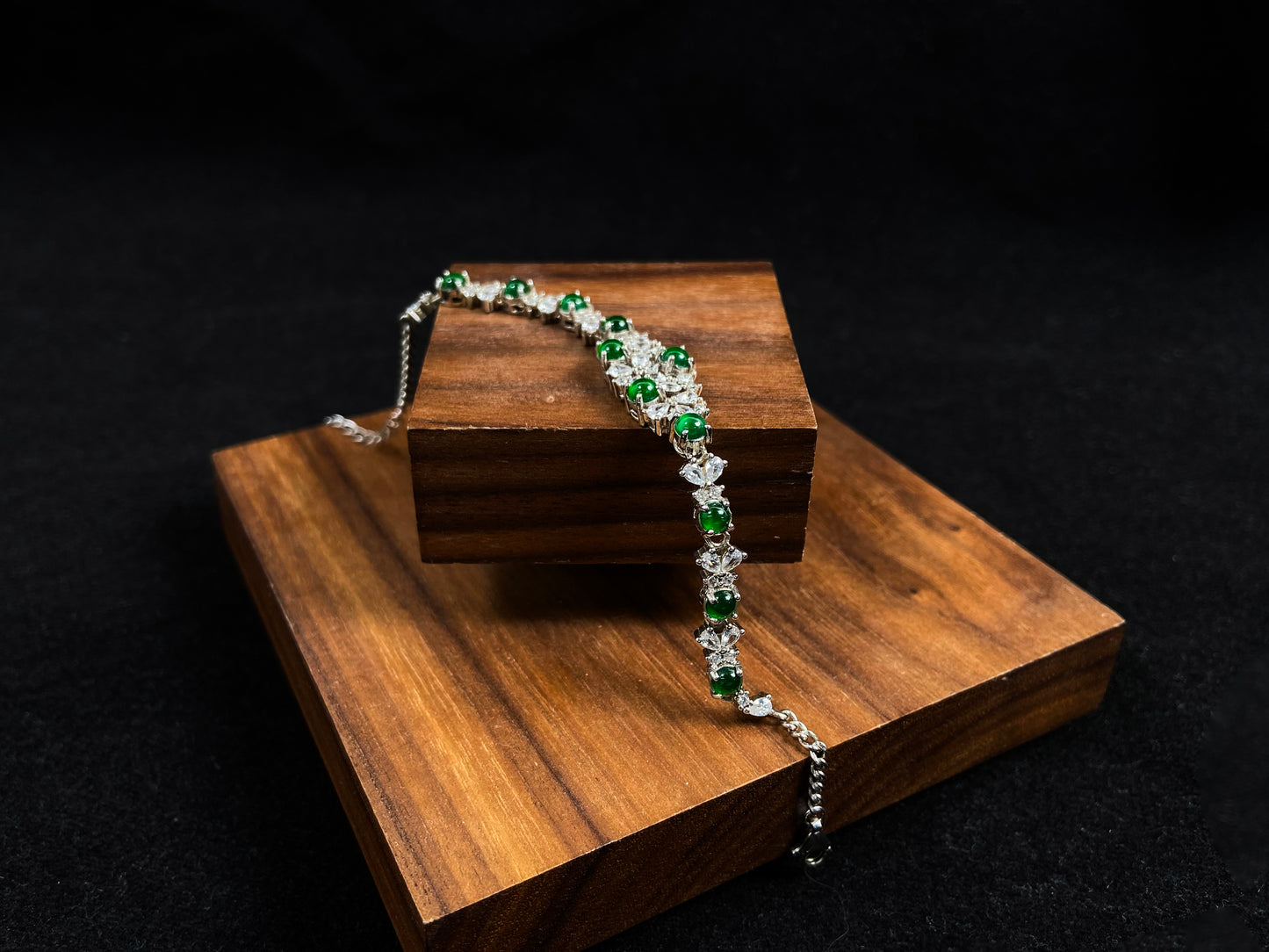 This elegant bracelet features green jade cabochons claw-set in 925 silver, with petal-shaped settings adorned with diamonds.