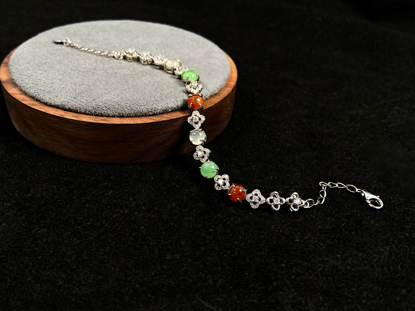 A jadeite bracelet with brown, green, and icy cabochons, each separated by sterling silver flowers set with diamond centers.
