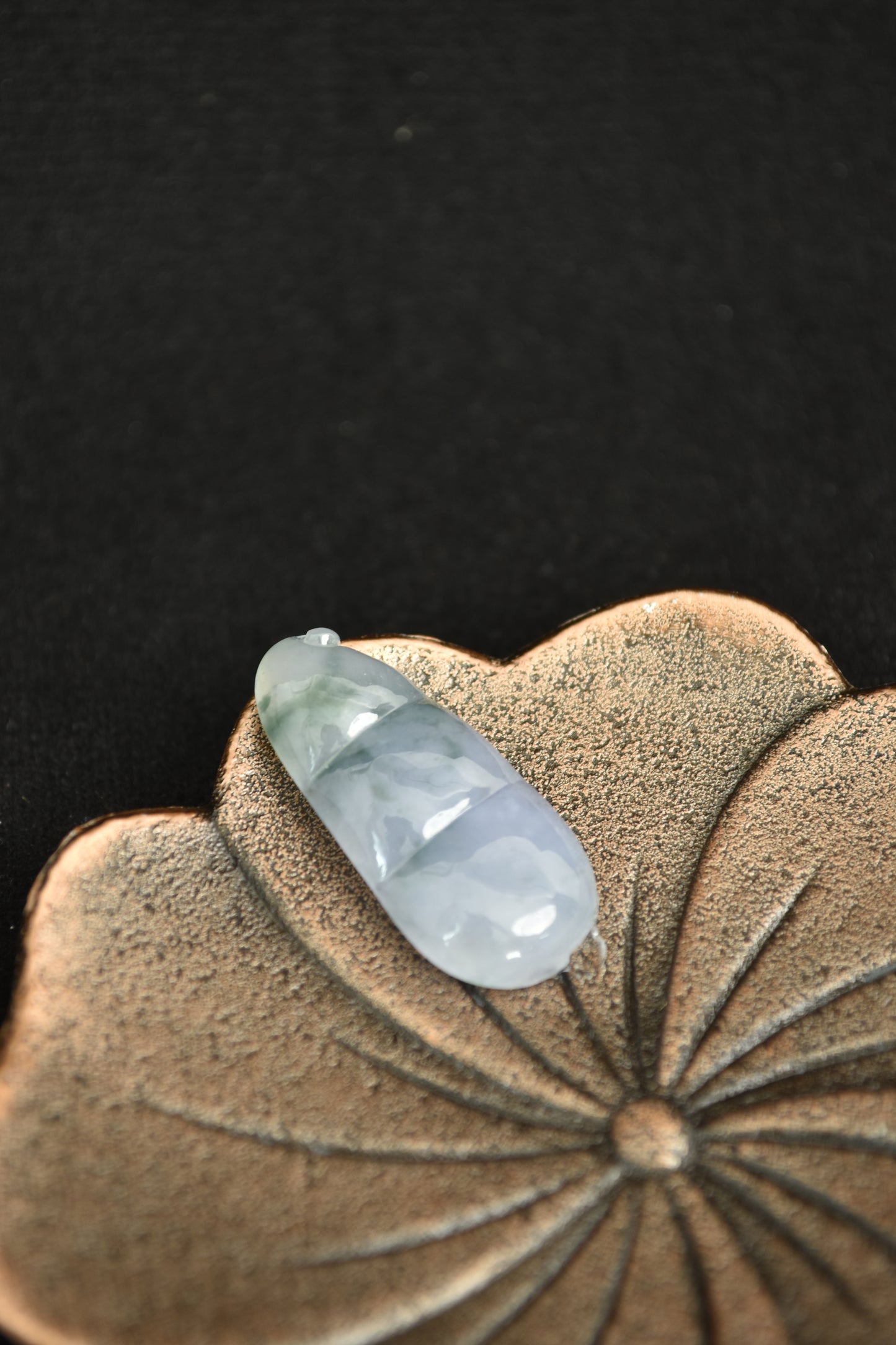 Decorative ceramic piece with a teardrop-shaped stone on a dark background