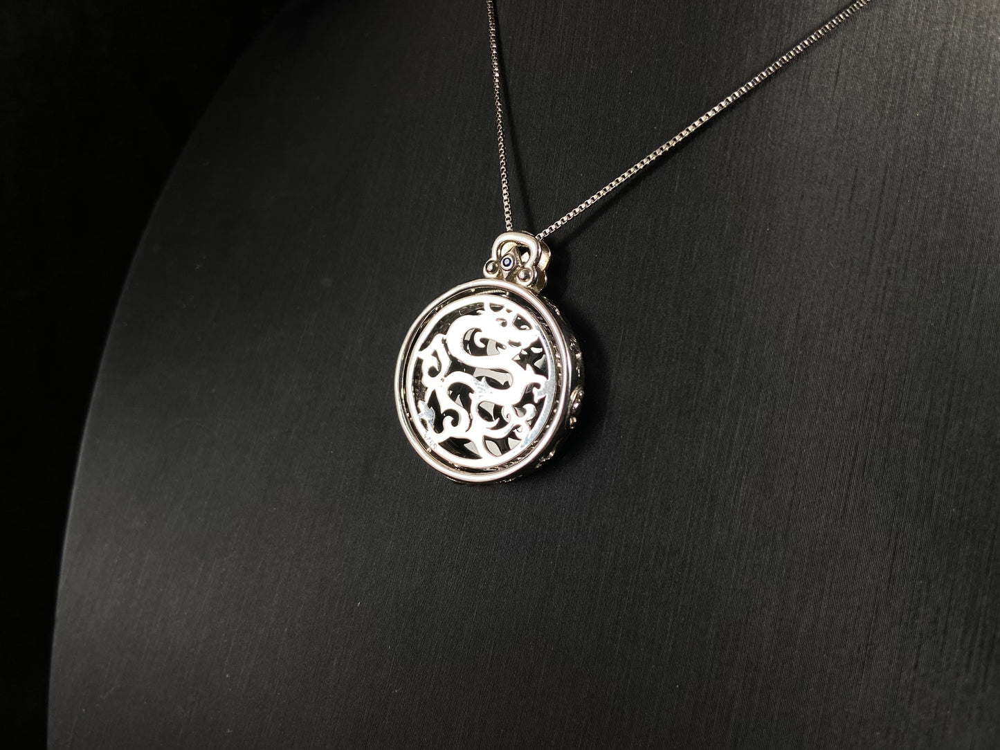 Silver necklace with a round pendant on a dark gray background