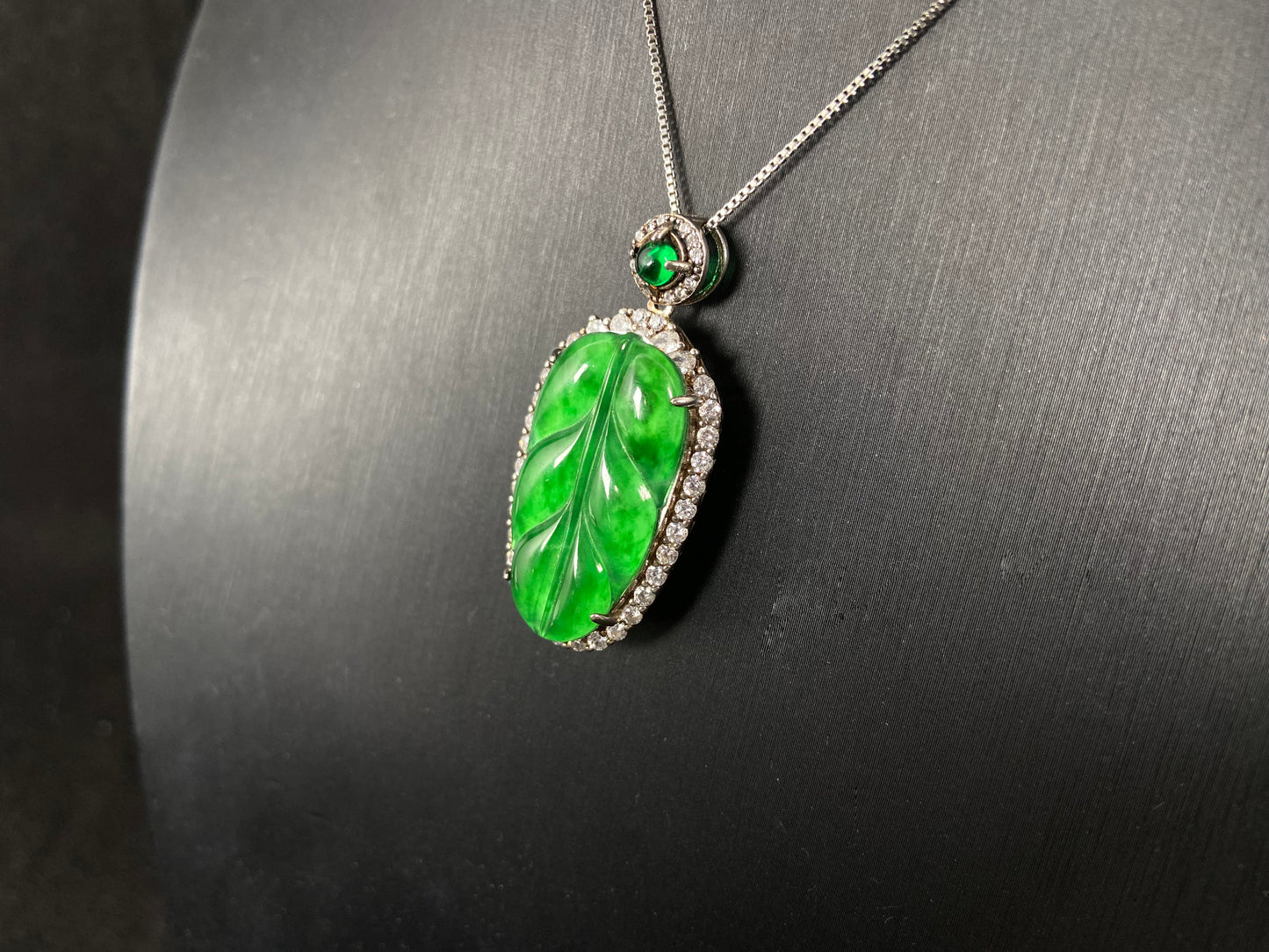 A leaf shaped emerald jadeite pendant, elegantly framed by a 925 sterling silver border.