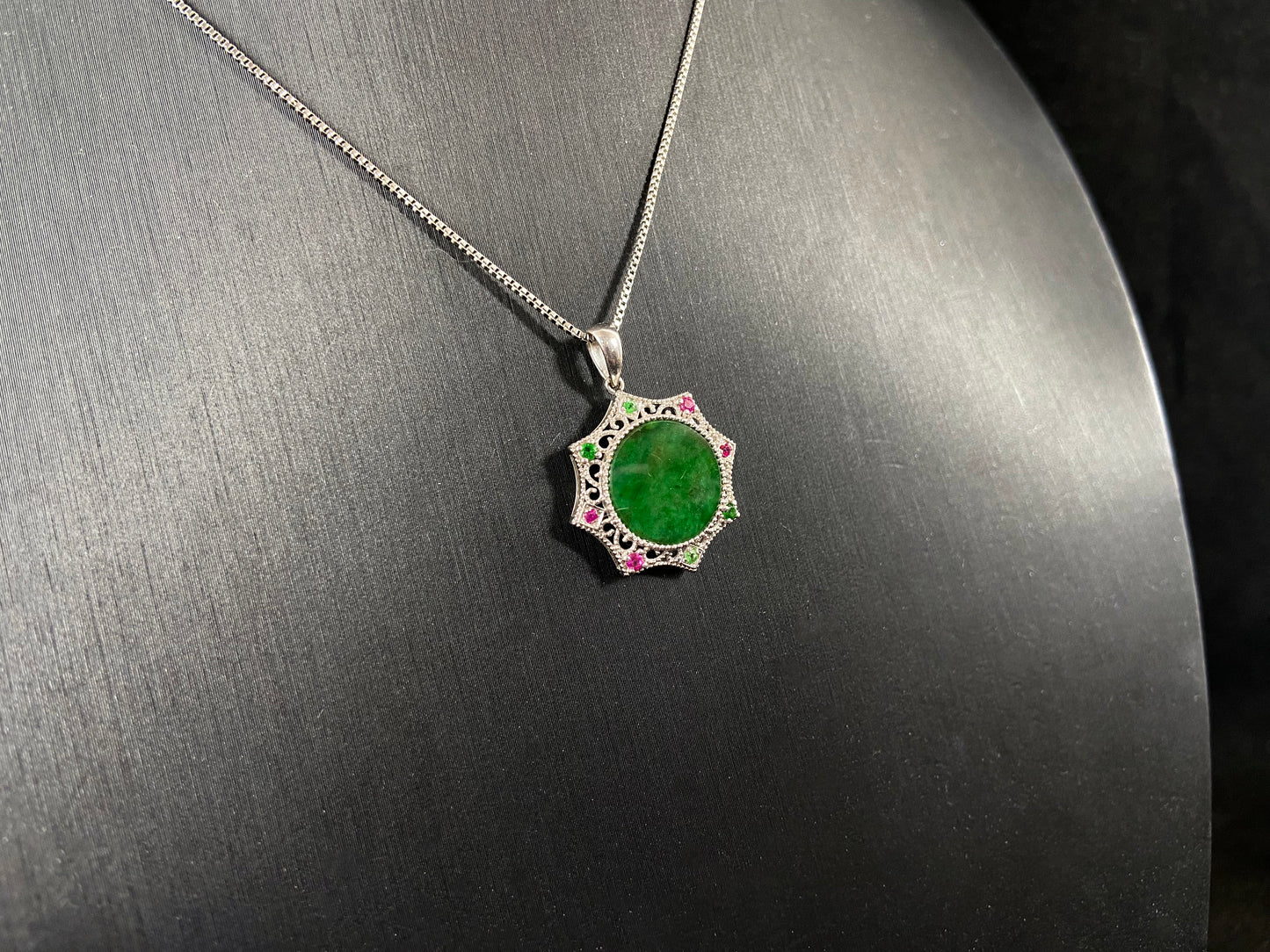 A circular imperial green jade center is elegantly encased within an octagonal frame of 18k white gold.