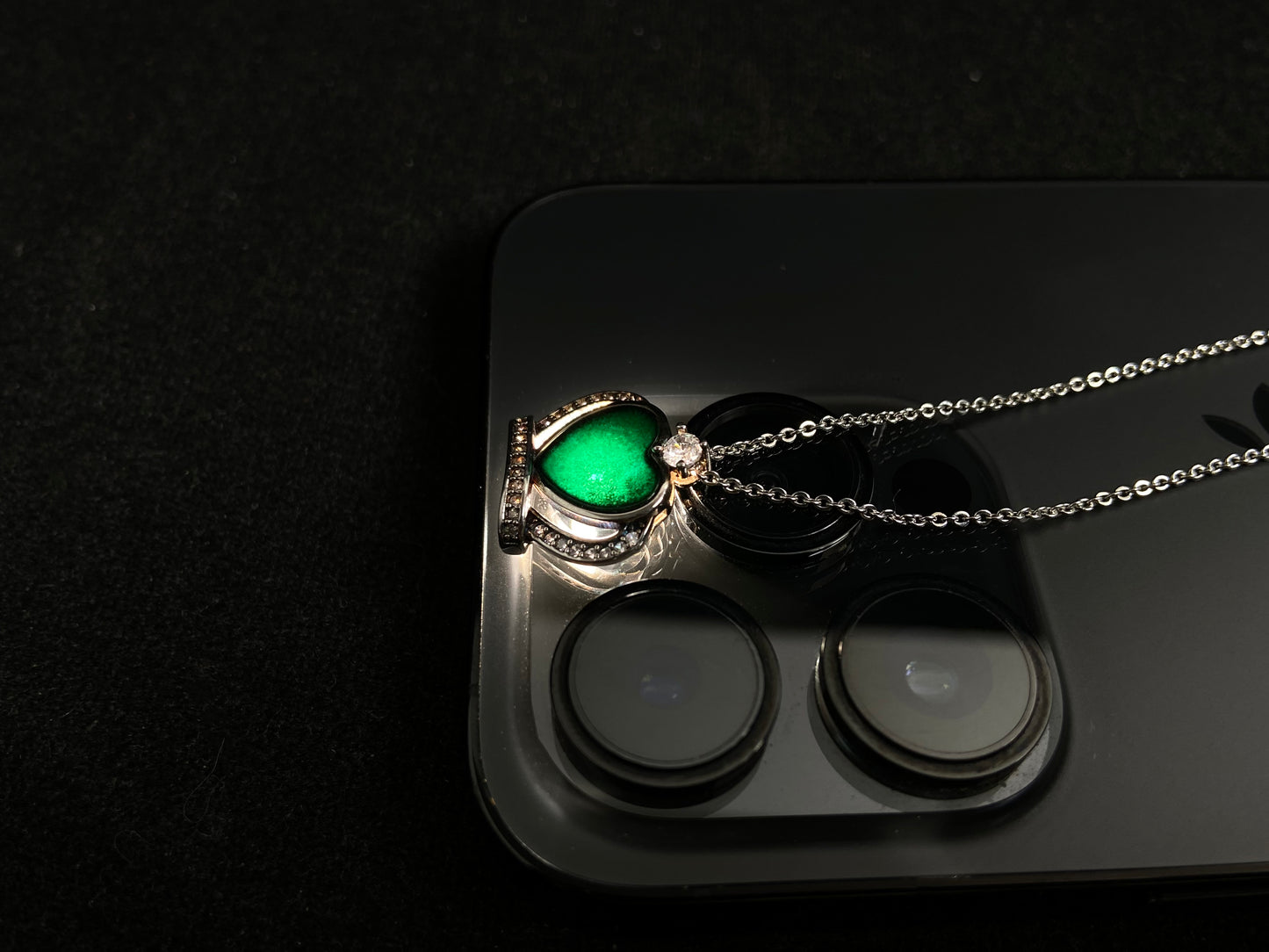 A heart shaped mystical jade pendant set in 925 silver with a diamond accent, revealing a hidden green glow when illuminated.