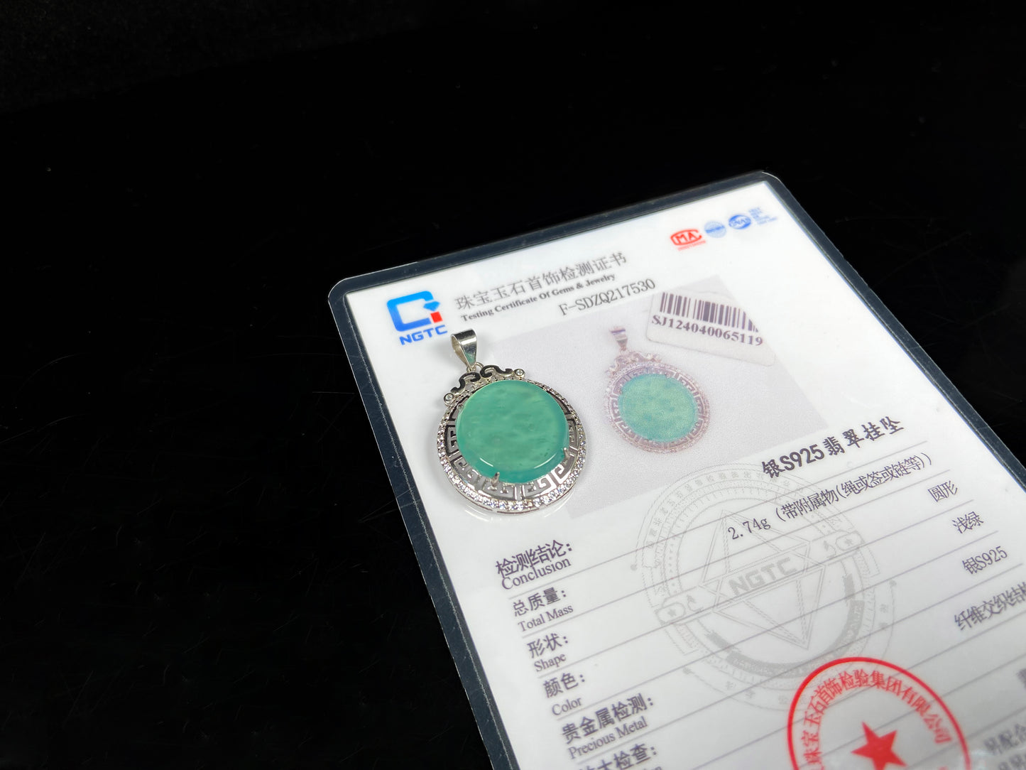 Jade pendant on NGTC with certification details against a black background