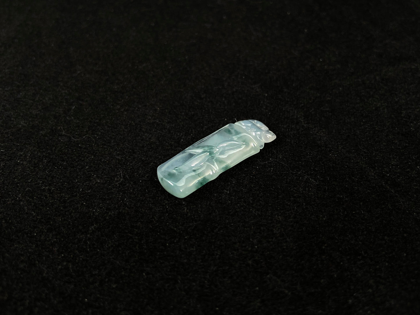 A translucent bamboo shaped jade pendant with floating green accents, symbolizing continual growth and career success.