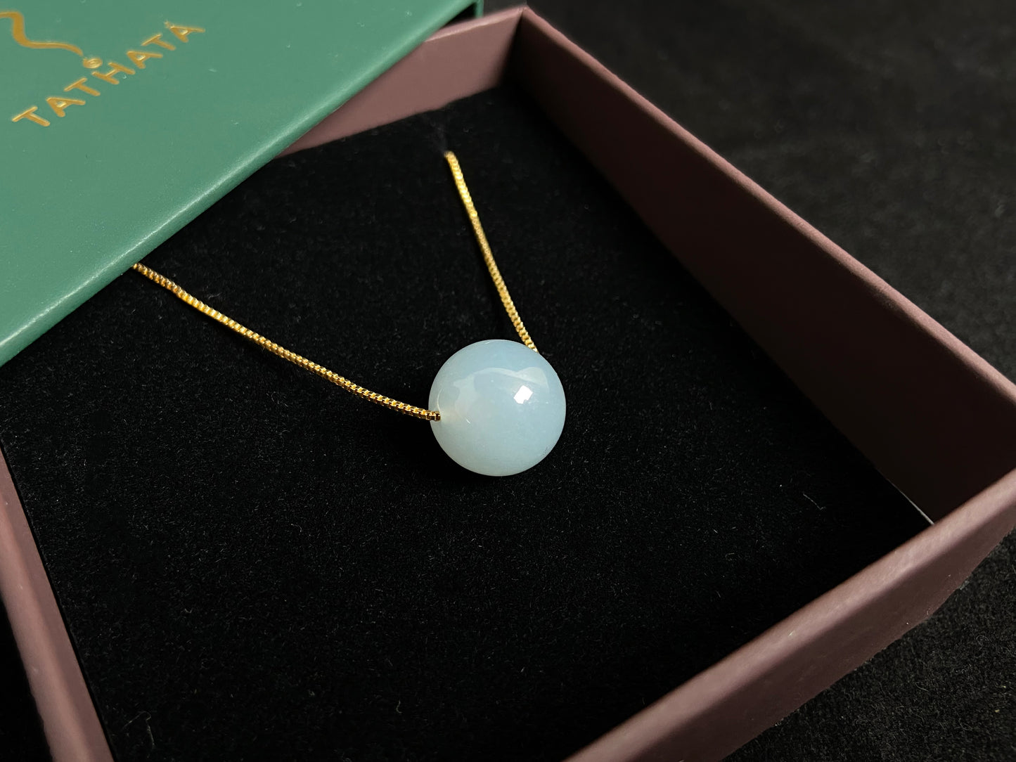 A single milky white jade bead pendant, smooth and luminous.