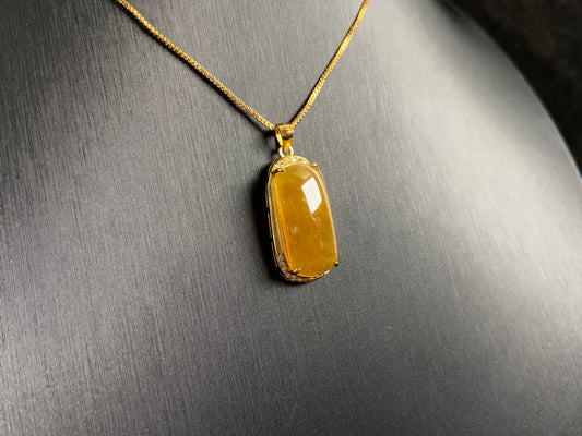 A golden yellow jade centerpiece, elegantly embraced by a gold plated 925 silver frame.