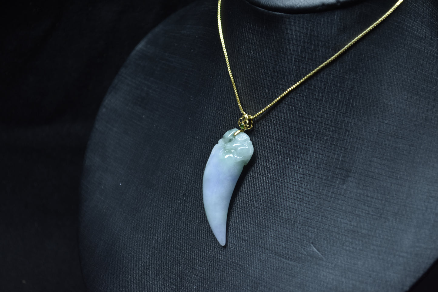 This jadeite pendant features a shark tooth shape in white, purple, and green.