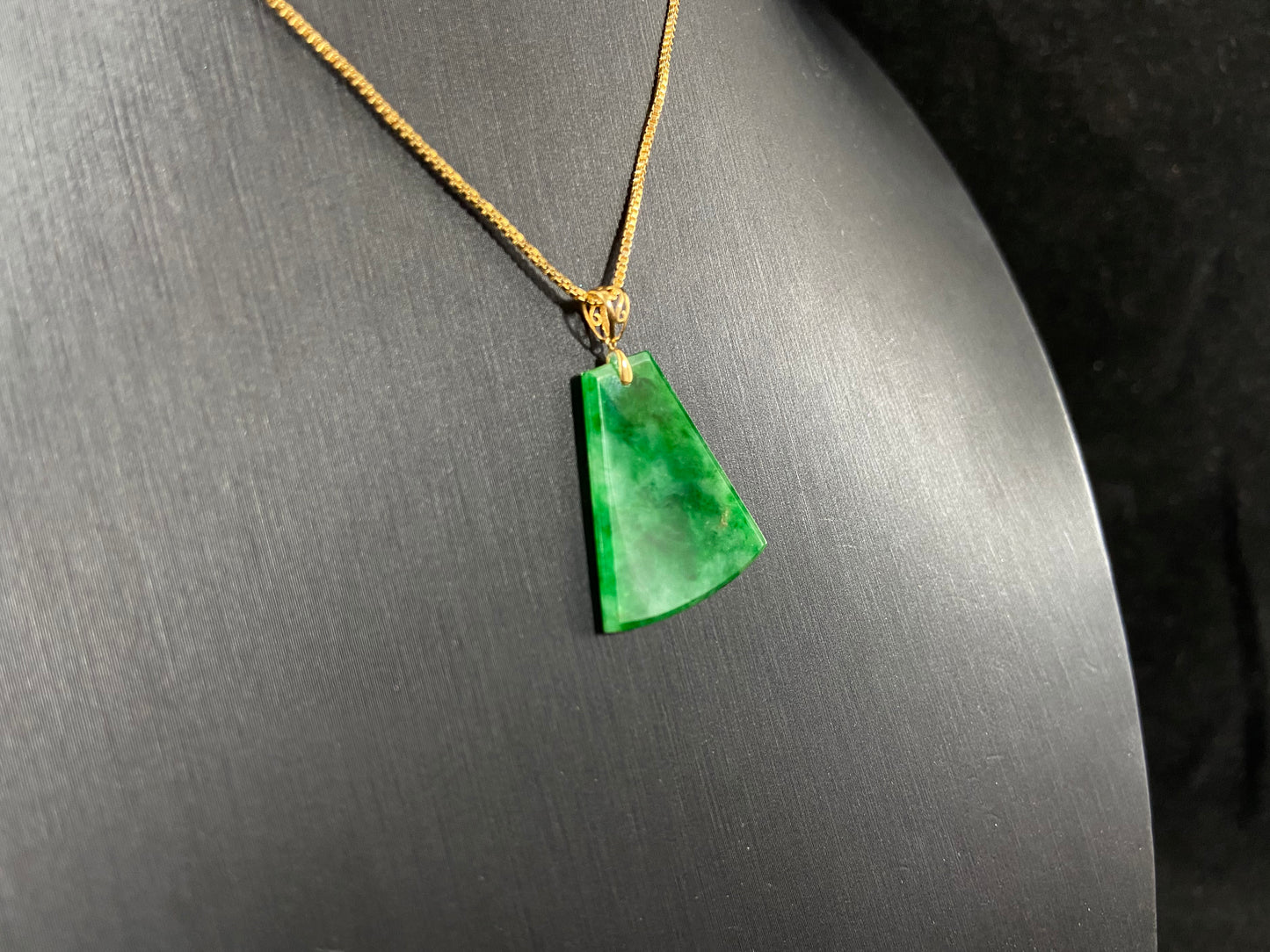 A light green jade plaque with darker green veining, featuring a gold plated 925 silver bail.