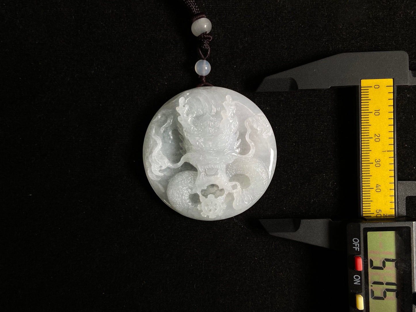 This exquisite pendant features a circular milky white jade disc intricately carved with a majestic dragon head design.